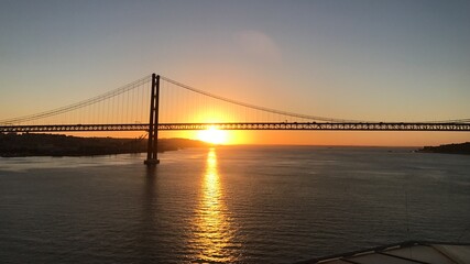 Portugal Lissabon Brücke des 25. April Hängebrücke Metall über dem Fluss Tejo von einem Kreuzfahrtschiff aus am Morgen bei Sonnenaufgang am Horizont
