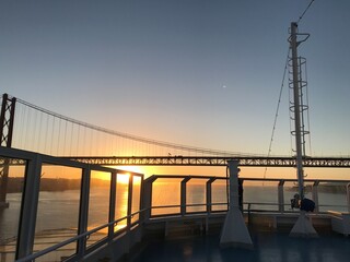 Fototapeta na wymiar Portugal Lissabon Brücke des 25. April Hängebrücke Metall über dem Fluss Tejo von einem Kreuzfahrtschiff aus am Morgen bei Sonnenaufgang am Horizont