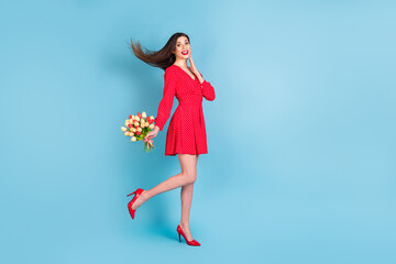 Full length body size profile side view of pretty amazed cheerful girl holding tulips walking...
