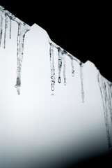 Monochrome image of melting icicles on the roof.