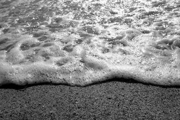 Coming wave and beach sand in black and white.