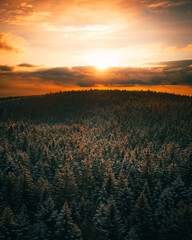 The Aerial view of snow-covered winter forest in time sundown on Christmas Eve.