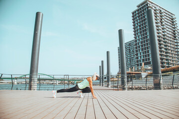 Woman in sportswear doing exercises near the river. Healthy lifestyle concept.