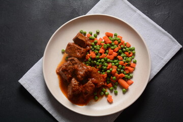 Spicy beef stew with boiled carrots and peas. Healthy food