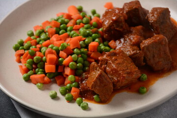 Spicy beef stew with boiled carrots and peas. Healthy food