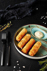 cheese sticks with sauce in a plate on a black textured background