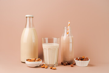 Various vegan plant based milk and ingredients. Dairy free milk substitute drinks on pink background