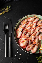 shrimp in a plate on black textured background top view