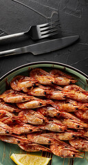 shrimp in a plate on black textured background with fork and knife top view