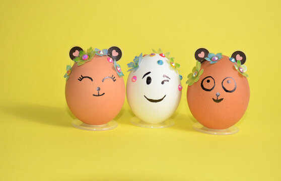 Three Easter eggs with cute faces on a yellow background. Spring. Easter.
