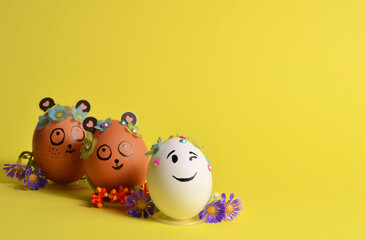 Three Easter eggs with funny faces on a yellow background. Spring. Easter.