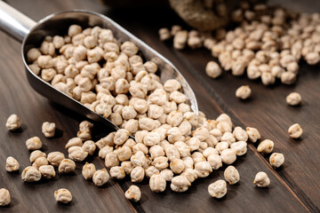 Uncooked Chickpeas on scoop on rustic wooden table. Rustic still life