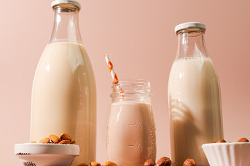 Variousnon dairy vegan plant milk and ingredients on pink background, closeup view