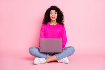 Full size photo of young happy excited shocked positive girl working in laptop sit floor isolated on pink color background