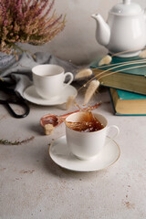 Still life with tea splashing out of tea cup, books and flowers