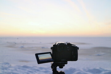 winter snowy landscape, camera in the foreground shooting golden hour