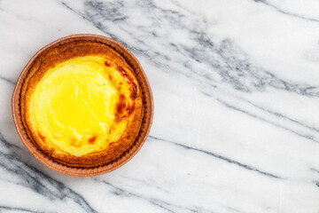 Egg tart, traditional Portuguese dessert, pastel de nata in a gray plate on a marble background . Portuguese puff close-up. Selective focus, copy space