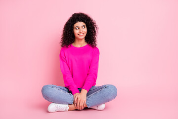 Fullsize photo of young lovely smiling dreamy girl sit floor with crossed legs look copyspace isolated on pink color background