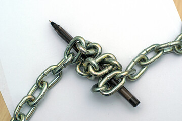 Obraz premium a fountain pen wrapped with an iron chain on sheets of white paper concept freedom of speech