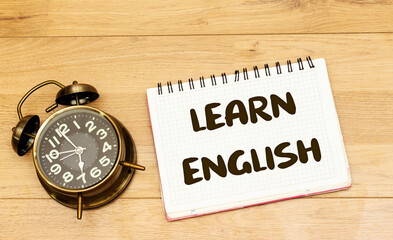 learn english concept on notebook with alarm clock showing 7 am or pm