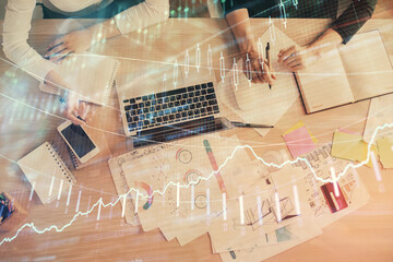 Double exposure of woman hands working on computer and forex graph hologram drawing. Top View. Financial analysis concept.