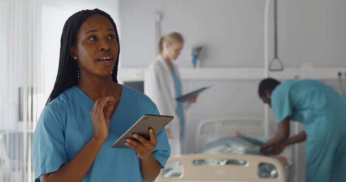 Afro-american woman surgeon holding tablet and talking at camera