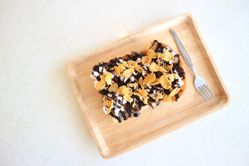 Toasts bread with cornflakes and chocolate on white wooden table