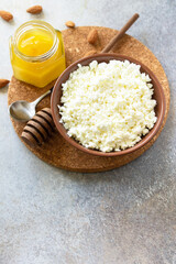 Rich in calcium healthy food. Tvorog, farmers cheese, curd cheese or cottage cheese in a bowl with honey and almond on stone table. Copy space.