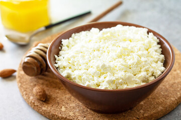 Rich in calcium healthy food. Tvorog, farmers cheese, curd cheese or cottage cheese in a bowl with honey and almond on stone table.