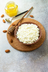 Rich in calcium healthy food. Tvorog, farmers cheese, curd cheese or cottage cheese in a bowl with honey and almond on stone table. Copy space.