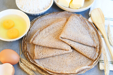 A traditional French region of savory Buckwheat Galettes Bretonnes with eggs, flour and butter with wheat plant on a preparation table