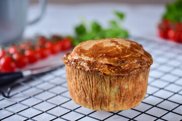 An English pie with minced meat and meat, made from shortcrust pastry, lies on a black metal...