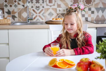 Beautiful delighted little blonde girl laughs and has a healthy breakfast. Love for fruits. Orange. Orange mood