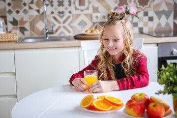 Beautiful delighted little blonde girl laughs and has a healthy breakfast. Love for fruits. Orange. Orange mood