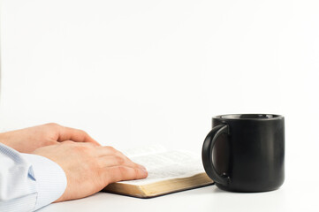 Fototapeta na wymiar Open holy bible book on a white table. Scripture. Hands in prayer. A cup