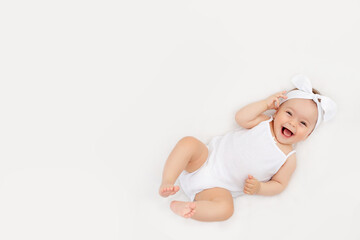 smiling baby on a white bed at home, the concept of a happy, healthy baby, a place for text