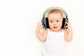 baby with headphones listening to music on a white bed at home, a place to text