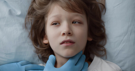 Top view of doctor touching child neck lying in hospital bed 