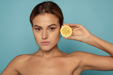 Fototapeta na wymiar Beauty, skin care and detox concept. A beautiful girl holds juicy lemon near her face