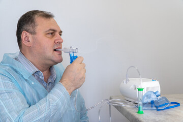 man holds a breathing tube and inhales. nebulizer and Oxygen Mask. spraying of a drug that is...
