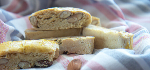 Sweet biscotti cookies and almonds on striped kitchen towel. Side view
