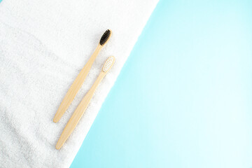 White towel and de bamboo toothbrushes on a light blue background with copy space. Ecology concept.