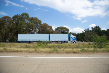 Truck on a freeway with plane flying overhead in Australian Country Town midway between Sydney and Melbourne with nice blue sky and lush green trees as a backdrop