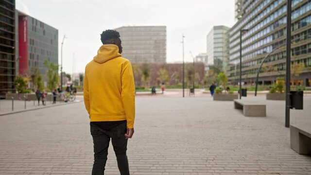 Back shot of Stylish portrait of a cool black african american man in a downtown city center. Shot in 4k. City exploring