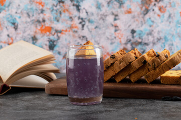 Close up photo of fresh grape cocktail with sliced cake and book