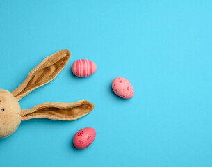 long fur bunny ears on a blue background and pink decorative eggs