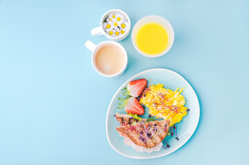 Coarse bread toast with ham, salad and scramble, sprinkled with sprouted seeds. Super food, aromatic coffee and a glass of orange juice. Delicious healthy breakfast on a bright background.
