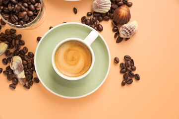 Small Cup of aromatic espresso coffee with froth. Traditionony is an Italian breakfast drink with shell-shaped chocolates. Top view. Copy space