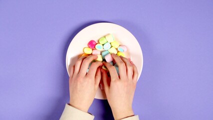 Hands are taking candies in a plate