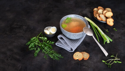 Homemade chicken broth or bouillon with spices, herbs, dill, parsley, onions and microgreens on a...